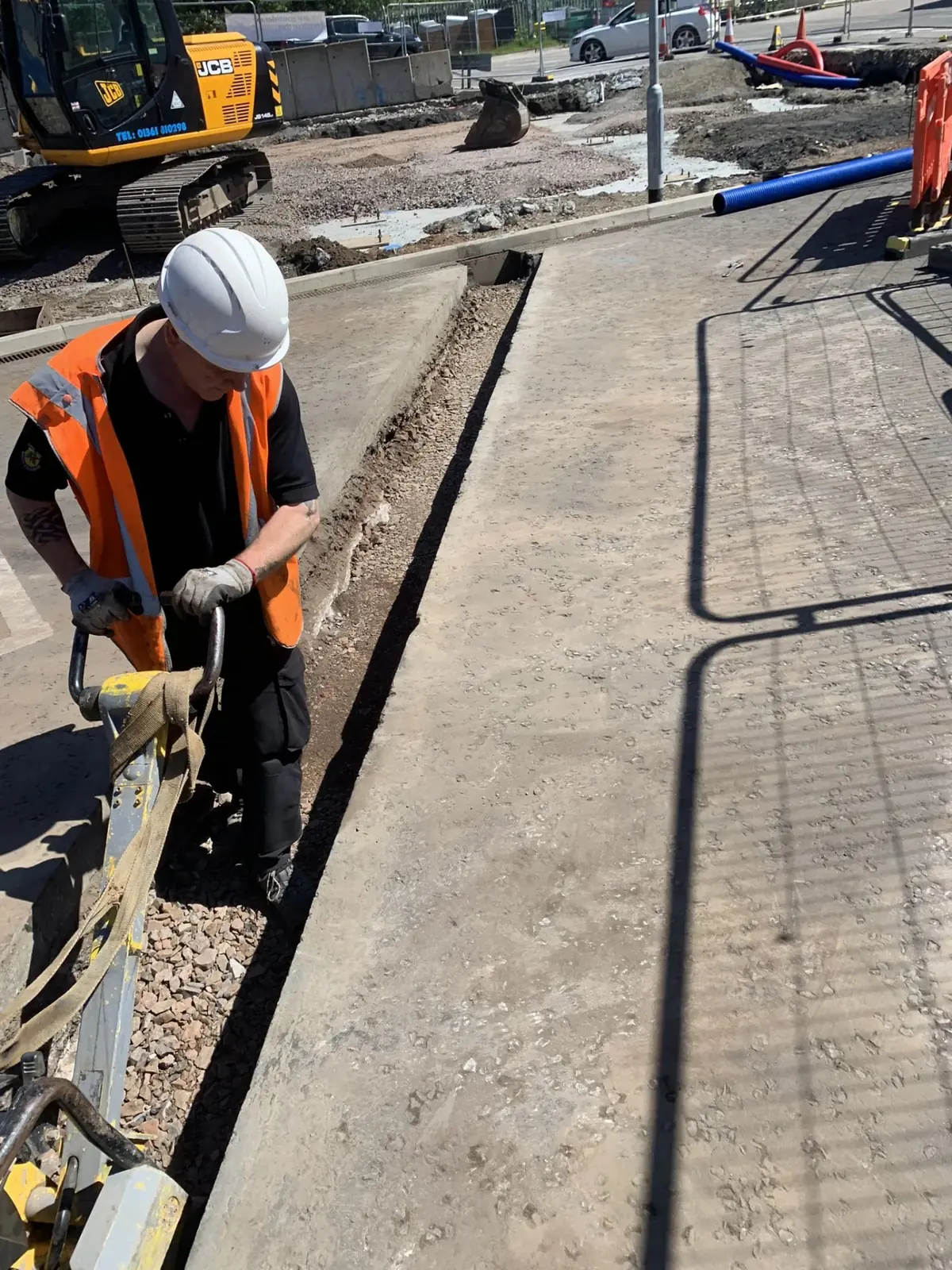 B&K Hume groundworker finishing the edge detail beside a newly laid concrete footway